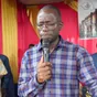 Pasteur Aly Thomas Koniono en prière au pupitre, micro en main